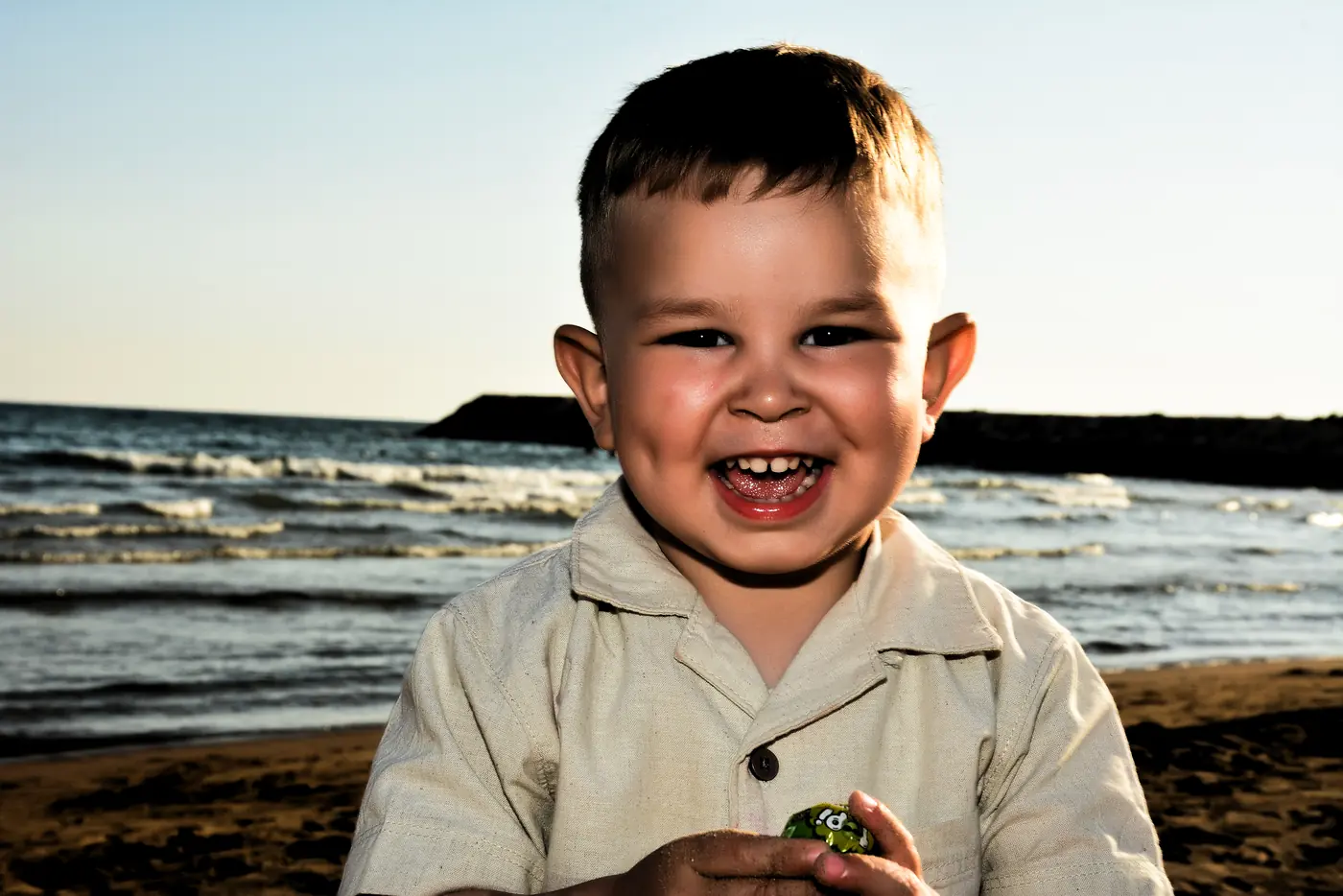 Lachender Junge am Strand im Abendlicht