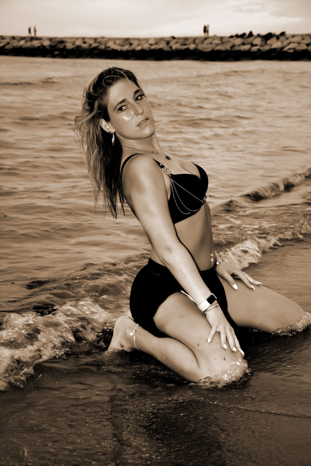 Frau sitzt im seichten Wasser am Strand